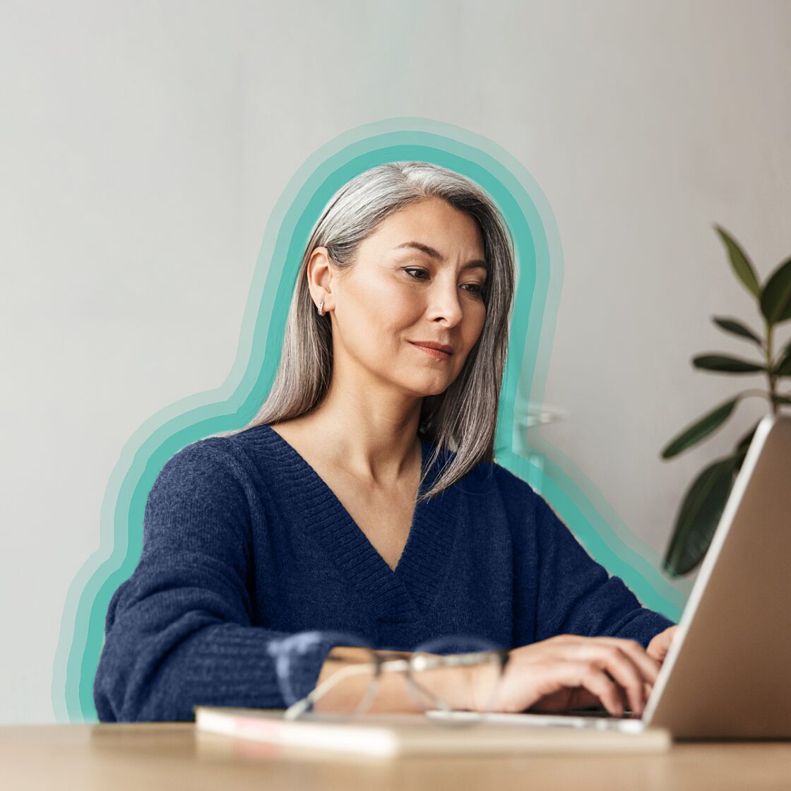 Silver-haired woman working on a laptop at a desk.