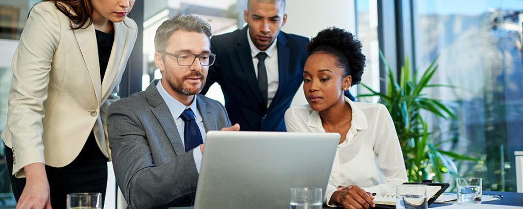 Four people looking at a laptop presentation.