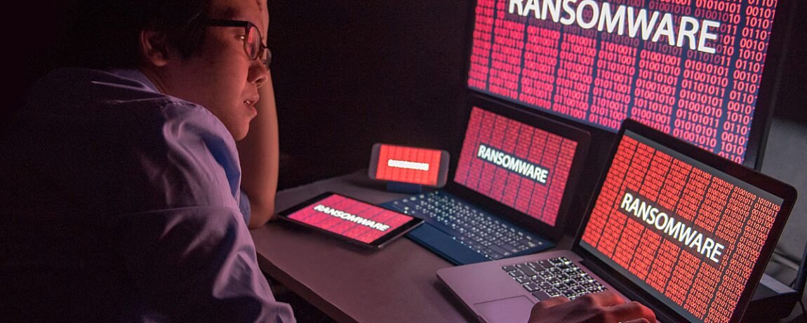 A guy sitting in front of his computer with "Ransomware" displayed on the screen.