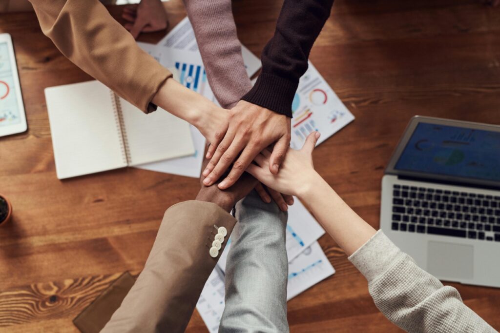 Team's hands coming together in the middle of a desk