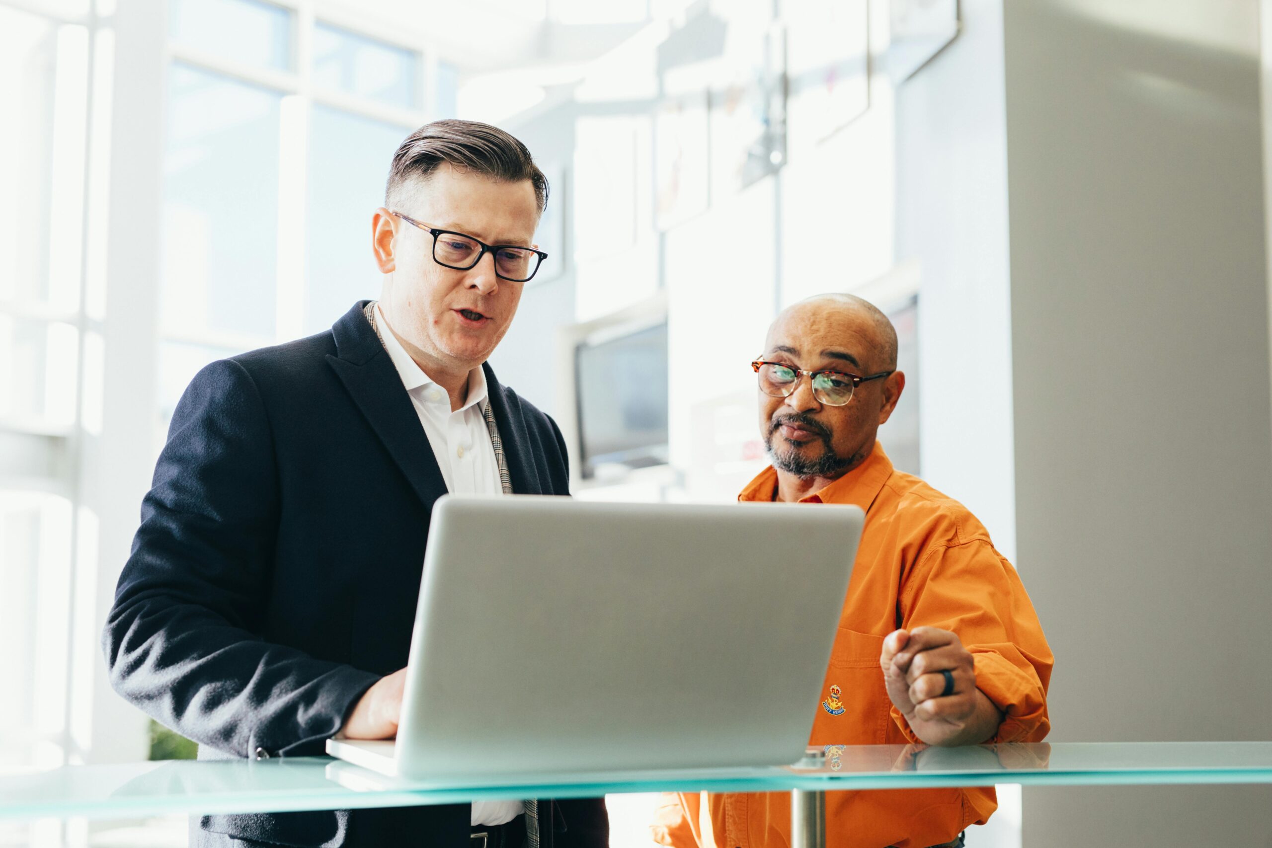 two men talking in front of computer