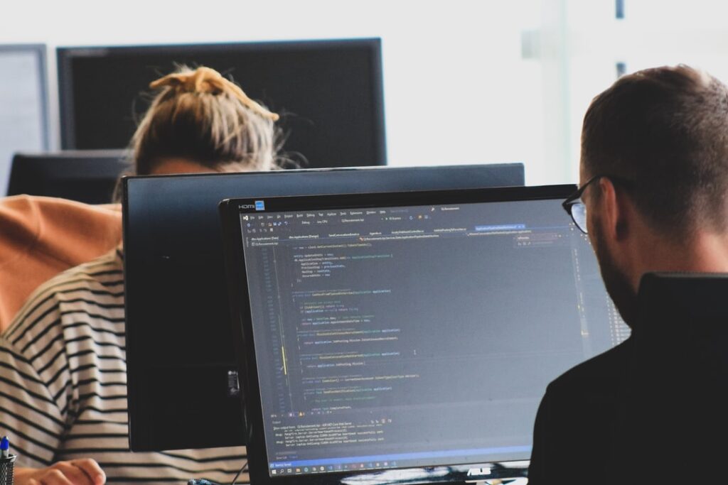 two people at computers coding