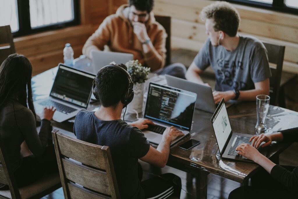 Five people sitting around a table with laptops.
